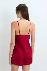 Conjunto de pijama de satén color rojo, compuesto por un top con breteles finos y escote en V adornado con puntilla, y un short con cintura elastizada y lazo regulable.