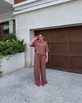 Conjunto de dos piezas color crema, compuesto por una remera de mangas cortas con logo bordado en el pecho y un pantalón palazzo con cintura elastizada y cordón ajustable.