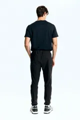 Pantalón de jogging deportivo negro de corte ajustado, confeccionado en tejido funcional DryMove™ que absorbe el sudor. Cuenta con cintura elástica con cordón de ajuste, bolsillos laterales, bolsillos con cierre en las piernas y bajos elásticos.