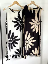 Vestido corto tipo musculosa con estampado de hojas de palmera en blanco y negro, con corte asimétrico.