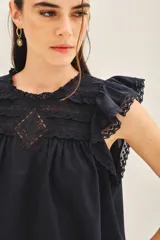 Camisa blanca de algodón con escote redondo, mangas cortas con volados y detalles de puntilla en el canesú.