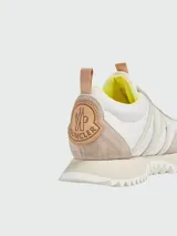 Zapatillas urbanas Moncler modelo Pacey, color blanco con detalles en beige y amarillo. Confeccionadas en cuero y tela, con cordones y suela de goma.