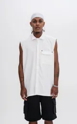 Camisa blanca sin mangas de calce oversize con doble bolsillo y detalle de remaches en el frente, confeccionada en tejido twill de alta calidad.