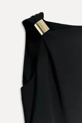 Vestido midi negro de viscosa, con escote asimétrico, manga sisa, detalle metálico en el hombro, tejido drapeado y cierre lateral con cremallera oculta.
