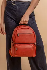 Mochila color marrón de símil cuero con un compartimento principal amplio, bolsillo al frente con cierre, correas ajustables y asa.