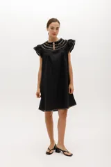 Vestido negro de lino, corte suelto, con cuello redondo con volados y mangas cortas con volados.