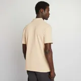 Remera de hombre color beige claro, de punto piqué, con cuello polo y mangas cortas.