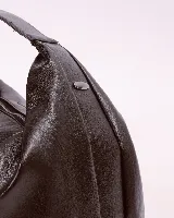 Bolso marrón oscuro de cuero sintético con forma ovalada y asa corta.
