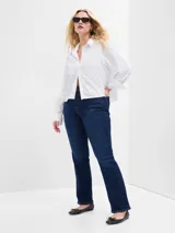 Camisa blanca de poplin, corte crop, con cuello clásico, cierre frontal con botones y mangas 3/4 con puños abotonados.