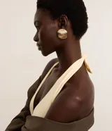 Aretes tipo botón redondos de bisutería, color dorado claro, con textura de líneas verticales acanaladas.