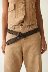 Cinturón negro de cuero vacuno con diseño calado y cordón entrelazado.