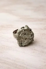 Anillo ajustable de alpaca con una piedra cruda de pirita engarzada, caracterizada por su textura rugosa y brillo metálico dorado.