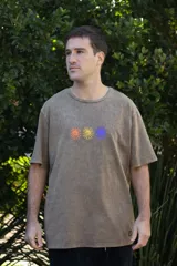 Remera color arena con efecto gastado, de manga corta y cuello redondo. Estampado frontal con tres soles de colores: naranja, amarillo y violeta.