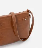 Bolso bandolera pequeño color marrón con textura de piel de cocodrilo, correa fina ajustable, cierre de cremallera y hebillas laterales decorativas.