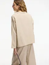 Camisa beige de algodón con botones frontales y cuello camisero.