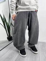 Pantalón de jean gris oscuro, corte holgado, con bolsillos delanteros y traseros. Presenta un bordado de una cruz ornamentada en el bolsillo trasero derecho.