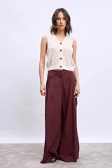 Chaleco de tejido de punto color crudo, sin mangas, con escote en V y cierre frontal de botones marrones.