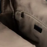 Mochila negra de cuero sintético con diseño acolchado en la parte inferior. Tiene un asa de mano, correas regulables, cierre principal y tres bolsillos externos con cierre. El interior está forrado y cuenta con un bolsillo con cierre y dos bolsillos abiertos.