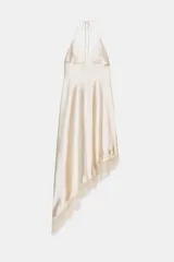 Vestido midi de seda color crema, con escote pronunciado en pico y tirantes finos ajustables tipo halter. El bajo es asimétrico y está adornado con un delicado encaje a tono.