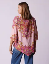 Blusa de gasa estampada con cuello a la base, escote en V y botón. Manga ¾ con terminación amplia y ruedo en pico.