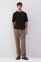 Pantalón marrón claro de lino, corte recto, con cintura elástica y cordón ajustable. Posee bolsillos laterales y trasero.