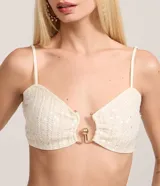 Blusa tipo crop top de color blanco hueso, con textura de tejido de punto y lentejuelas. Presenta escote corazón con un detalle metálico dorado en el centro que simula un cierre abierto. Tiene tirantes finos ajustables.