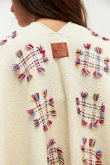Ruana color crudo con flecos y bordados florales multicolores.