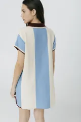 Vestido corto tejido en jersey liviano de algodón y acrílico, con diseño tipo polo y fit holgado. Presenta rayas verticales en color marrón y crudo, bordado XL de un ají y terminaciones en color amarillo.