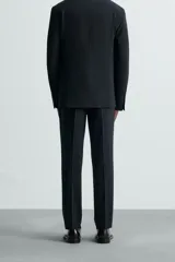 Pantalón de vestir gris oscuro, corte slim fit, confeccionado en tejido con 17% de lana. Cuenta con bolsillos frontales y traseros de vivo con botón. Cierre frontal con cremallera y botón.