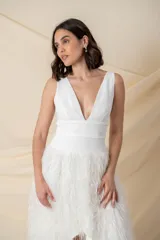 Vestido blanco de crepe con escote profundo y falda irregular con flecos brillantes. Se puede usar con pantalones por debajo.