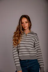 Sweater gris con rayas horizontales blancas, cuello polo con cierre de cremallera y mangas largas.