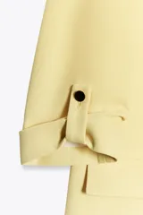 Blazer color marrón oscuro, de corte recto, con cuello solapa y hombreras. Tiene mangas 3/4 con trabilla y botón dorado, y bolsillos delanteros con solapa.