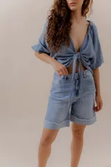 Bermuda de denim celeste, de tiro medio, corte relajado y largo por encima de la rodilla. Presenta doble ruedo con detalle desflecado.