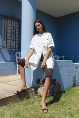 Camisa negra de algodón con cuello mao y mangas cortas. Presenta un pequeño bordado de una flor blanca en el pecho.