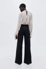 Jean de denim de algodón negro con leve stretch, pierna ancha, corte ajustado de cintura a cadera y holgado de muslo a bajo. Tiene cintura de tiro alto con cierre y botón, y bolsillos de parche delanteros y traseros.