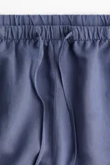Short azul de lino y viscosa, corte holgado, cintura elástica con cordón, bolsillos laterales y aberturas cortas en los bajos.