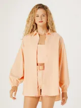Camisa naranja de corte oversize con cuello camisero y mangas largas.