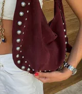 Bolso hobo color crema con tachas plateadas y cierre con botón magnético.