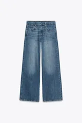 Pantalón de jean azul de tiro bajo, corte wide leg y largo hasta el tobillo. Tiene cinco bolsillos, trabillas en la cintura y cierre frontal con cremallera y botón metálico.