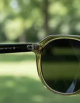 Lentes de sol unisex de forma geométrica, con armazón color mostaza oscuro y lentes polarizadas color negro.