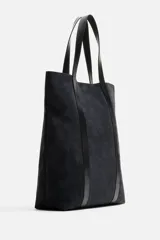Bolso tipo shopper fabricado en piel de alta calidad con acabado serraje color negro. Tiene compartimento principal con cierre de imán, bolsillo interior con cremallera y asas de mano de piel.