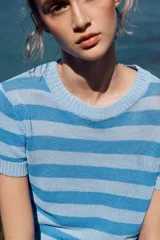 Top de punto celeste con rayas horizontales en azul. Tiene cuello redondo y mangas cortas.