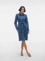 Vestido camisero de jean azul con cuello camisero clásico, mangas largas con puños abotonados, corte normal, abertura de tajo en la espalda, cierre con botones, cinturón incluido en la cintura y lavado a la piedra.