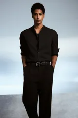 Camisa negra de corte estándar, con cuello mao, tapeta clásica y mangas largas con puños abotonados.