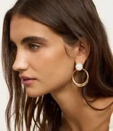 Aros dorados con base de resina blanca y colgante circular.