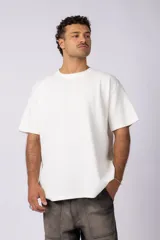 Remera de hombre color crudo, corte oversize, confeccionada en algodón grueso con textura micropanal. Diseño liso sin logos, con costura en forma de 'X' en la espalda. Ideal para un look casual y relajado.