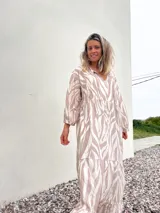 Vestido largo con estampado de cebra en tonos habano y crudo, corte amplio, cuello camisero y mangas largas.