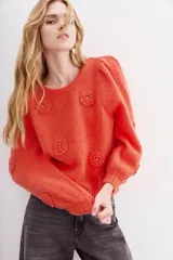 Sweater color coral de lana y mohair con calce holgado y mangas largas. Presenta frunces en hombros, escote, puños y ruedo en rib. Tiene aplicación de flores tejidas con detalle de strass.