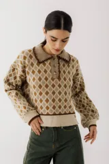 Sweater de punto color beige con diseño de rombos marrones, cuello polo con botones y mangas largas abullonadas.