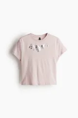 Remera corta rosa de algodón, con cuello redondo y estampado plateado en el frente.